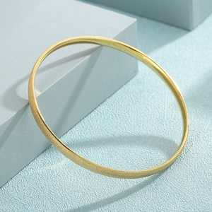 Detailed macro view of minimalist gold plated bangle with sparkling frosted sand finish