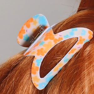 Pinza per capelli con fiori arancioni e blu indossata su lunghi capelli castani