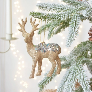 Glittery gold and silver reindeer hanging ornaments on a snowy Christmas tree branch