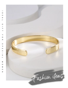 Detailed close-up of a minimalist gold-plated brass open C-shape cuff bracelet on stand