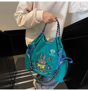 Close-up of teal canvas tote bag featuring cute rabbit embroidery and woven handles