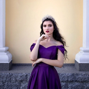 Elegant purple satin V-neck evening gown with off-shoulder design and rhinestone crown