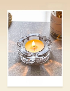 Close-up of a plum blossom shaped glass candle holder with a burning tealight