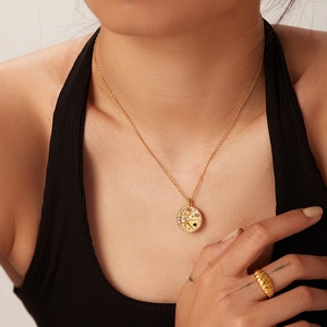 Gros plan d'un collier pendentif céleste doré et d'une bague texturée sur mannequin