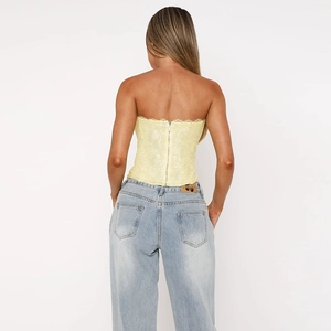 Détail du haut bandeau en dentelle jaune avec fermeture éclair et jean bleu