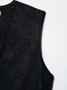 Dettaglio del gilet in camoscio nero con ricami floreali e borchie metalliche