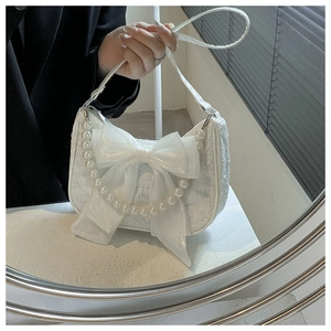 Detailed shot of white pleated handbag featuring a large mesh bow and decorative pearls