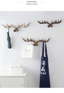 Detail of three vintage antler wall hooks in brown, tan, and grey with wood grain texture