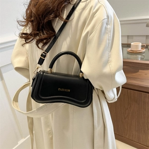 Elegant black leather handbag with curved base and golden fashion text on a model