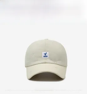Close-up of cream quilted baseball cap featuring diamond stitching and blue bird logo