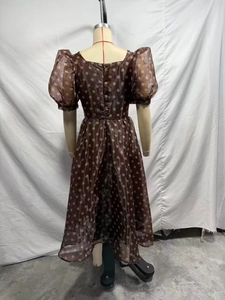 Detail of sheer brown organza dress with large white polka dots and puff sleeves