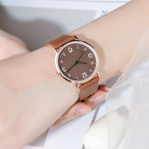 Close-up of a brown leather strap women's watch with golden case and brown dial on wrist
