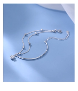 Detail of silver double-layered star bracelet with curved bars and beads on blue background