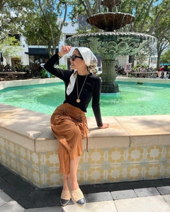 Detail of a white patterned satin silk scarf tied on a stylish lifestyle outfit
