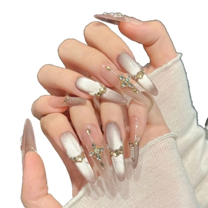 Silver cat-eye press-on nails with metal cross charms and pearl accents on almond shape