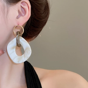 Close-up of model wearing irregular oval marble acrylic drop earrings with gold hoop
