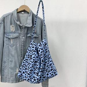 Blue leopard print canvas tote bag hanging on a denim jacket against a white wall