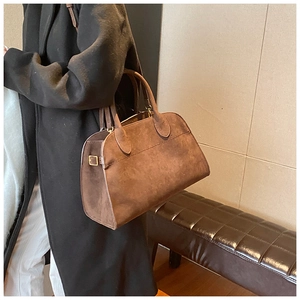 Dettaglio della borsa a mano in pelle scamosciata marrone con texture e design elegante