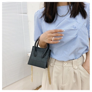 Close-up of black crocodile pattern small square bag with elegant gold chain strap