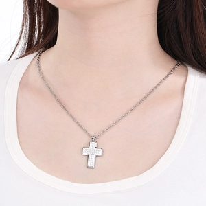 Close-up of a silver stainless steel cross pendant necklace worn by a model for a stylish look