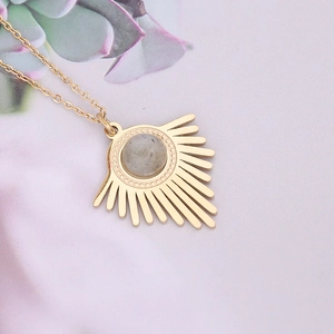 Detailed view of a gold sunburst pendant necklace with a round grey gemstone center