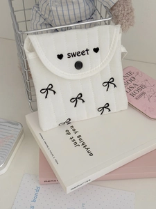 Detail of white quilted pouch with black bow and sweet embroidery on cotton fabric