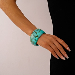 Close-up of a wide acrylic resin bangle with blue and brown marble texture on a wrist