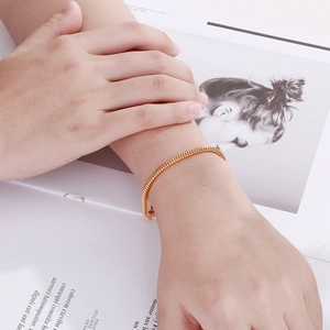 Close-up of golden snake chain bracelet on a model wrist with a fashion magazine backdrop