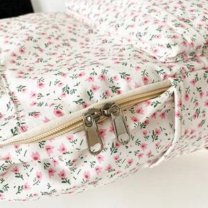 Close-up of durable silver metal zippers and floral canvas fabric on student backpack