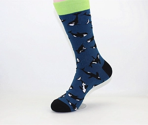 Detail of dark blue mid-calf socks featuring orca patterns and vibrant green ribbed cuffs