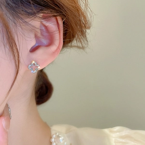 Macro shot of silver clover stud earring with sparkling pavé zircons on the ear