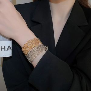 Detailed view of hollow butterfly wing patterns on gold and silver open cuff bracelets