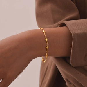 Close-up of a gold stainless steel four-pointed star bracelet on a woman's wrist