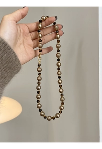 Détail du collier de perles champagne, pierres œil de tigre et fermoir doré brillant