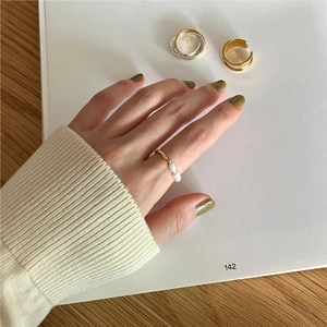 Detail of elegant 925 silver irregular pearl rings worn on fingers in a warm setting