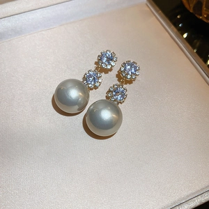 Détail de boucles d'oreilles fleur avec perles grises et cristaux dans un coffret