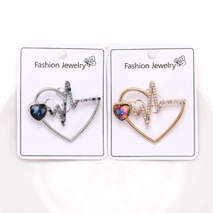 Detail of silver and gold heart brooches with blue and iridescent stones on display card