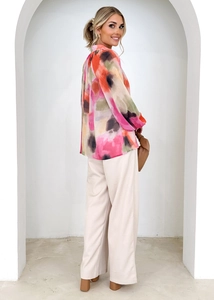Chemisier col en V à imprimé aquarelle assorti à un pantalon crème dans un cadre lumineux