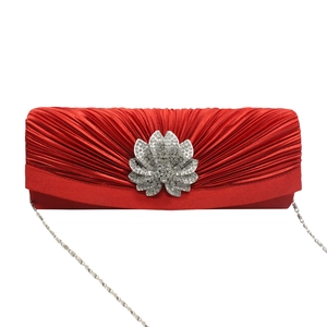 Detail of red pleated satin evening clutch bag with sparkling rhinestone flower clasp
