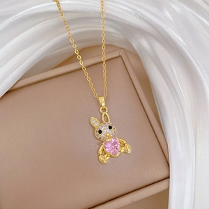 Macro shot of gold rabbit pendant with pink heart stone on white silk fabric
