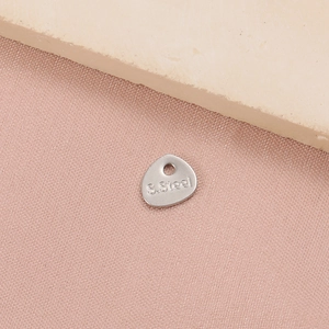 Macro shot of silver stainless steel teardrop pendant with S.Steel engraving detail