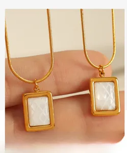 Gros plan du pendentif carré doré avec texture nacre blanche sur deux chaînes serpent