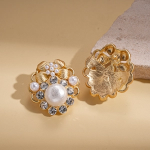 Detail view of retro gold flower stud earrings with faux pearls and sparkling rhinestones