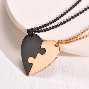 Macro shot of interlocking black and gold stainless steel heart puzzle pendants for friends