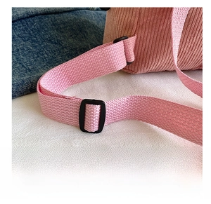 Detail view of the pink corduroy bag showing the adjustable woven strap and black buckle
