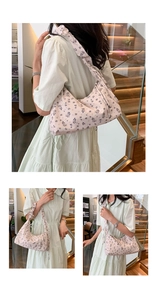 Floral underarm shoulder bag shown on model with light pink flower pattern and canvas texture