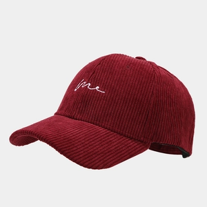 Vue détaillée de la texture du velours côtelé bordeaux et de la broderie blanche sur la casquette