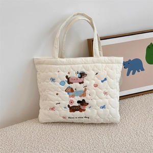 Detail of heart quilting texture and colorful dachshund embroidery on off-white tote bag