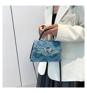 Détail du sac carré en denim bleu avec bords effilochés, étoiles et boucle nœud argent