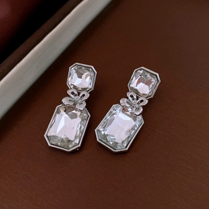 Vue macro de boucles d'oreilles argentées avec cristaux facettés et nœud délicat